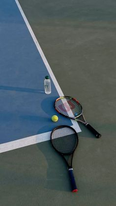 a tennis racket and ball laying on the ground next to a bottle of water