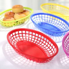 four different colored baskets with donuts in them on a white tablecloth and one is empty