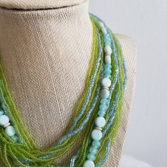 This is a vintage 1970's statement necklace. The primary strands of the necklace are a light green seed bead. The beads are very delicate but still in good condition. The other strands of the necklace are light blue tone beads. The clasp is a silver tone metal with the same green and blue beading covering the top of the clasp. Some of the beads are missing from the top of the clasp, but it is something that is not very noticeable given the placement. The necklace is in good condition.Measurement Blue Tone, Beaded Statement Necklace, Blue Tones, Green And Blue, Multi Strand, Wedding Necklace, Seed Bead, Light Green, Seed Beads