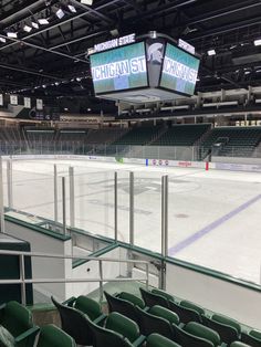 an empty ice rink with green seats and large screens on the wall above it that read michigan centre