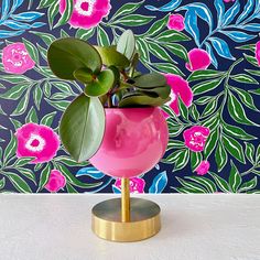 a potted plant sitting on top of a metal stand in front of a floral wallpaper