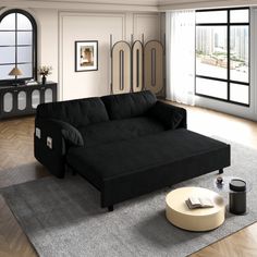 a black couch sitting on top of a rug in a living room next to a window