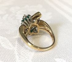 Emerald and diamond cluster ring. 14K yellow gold statement ring has 14 round vibrant green genuine emeralds, & 10 round shimmering diamonds in a free form design across the top of the ring. Below the gemstones is a detailed open airy under gallery. The design is like a bow with the ends being all high polished yellow gold. There is a beautiful rounded shank that tapers on the bottom to 2.5mm. Ring is a size 7 1/2 and can be resized 14 Emeralds app. .75cts have intense green color 10 Diamond Emerald Statement Ring, May Birthstone Rings, Emerald Rings, Gold Statement Ring, Ring Emerald, April May, May Birthstone, Form Design, Diamond Cluster Ring