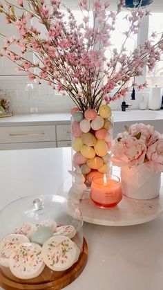 a table topped with cookies and flowers next to a candle