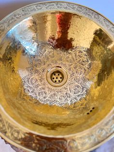 an ornate gold bowl sink on top of a marble counter