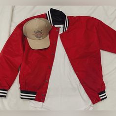 a baseball jacket and hat laying on top of a bed