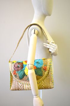 "Vintage 1970s straw shoulder bag, with raffia embroidered floral designs in bright colors. It is lined and has a snap closure. The bag is 13.5\" wide x 2 - 3\" deep x 10\" tall, with a 28\" long strap. Vintage straw bags are not great for everyday use or to carry heavy loads; age makes them more prone to breakage. ---> If you need an order shipped by a particular date or shipped via a quicker method, please ask PRIOR to purchase to see if we can accommodate that request. Visit the rest of ou Vintage Woven Crochet Bag For Summer, Vintage Crochet Beach Bag For Spring, Vintage Crochet Bag For Summer, Vintage Crochet Bag For Spring, Vintage Straw Bag For Vacation, Multicolor Embroidered Beach Bags For Summer, Vintage Multicolor Shoulder Bag For Summer, Vintage Woven Bags For Spring, Vintage Straw Shoulder Bag For Beach