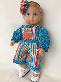 a baby doll with an orange flower in her hair is posed on a white background