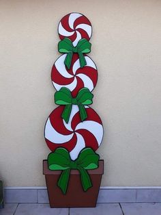 a large red and white candy cane on top of a potted plant in front of a wall