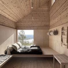 a bed sitting in the middle of a room next to a wooden wall and ceiling