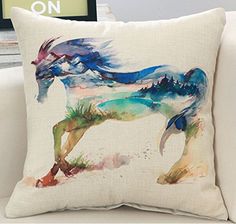 a pillow with a horse painted on it sitting on a couch next to a framed photo