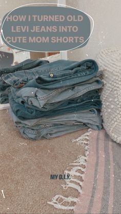 a pile of jeans sitting on top of a bed next to a pillow and blanket