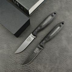 three knives sitting on top of a table next to a book and knife sharpener