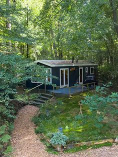 a small cabin in the woods with stairs leading up to it