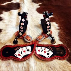 two pairs of shoes with playing cards on them sitting on a cowhide rug next to each other