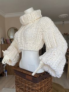 a mannequin wearing a white knit sweater and matching hat in a wicker basket