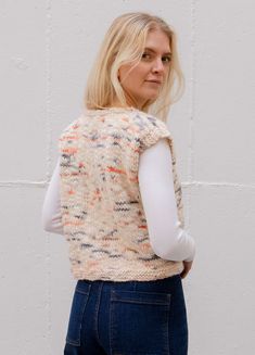 a woman standing in front of a white wall with her back turned to the camera