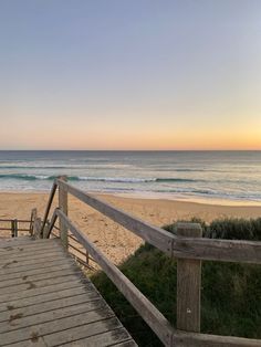 a wooden walkway leading to the beach at sunset