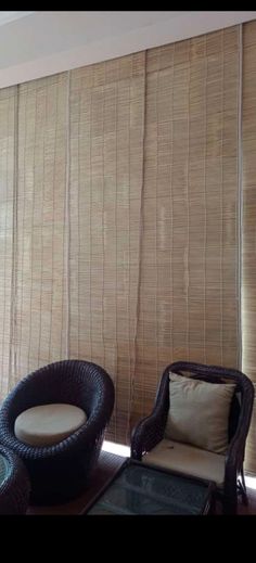 two wicker chairs sitting next to each other in front of a window with blinds