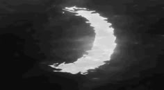 the moon is seen through some clouds in this black and white photo, taken from space