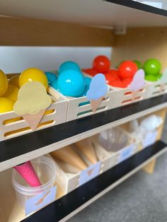 an assortment of colorful plastic balls and ice cream cones in bins on the shelf