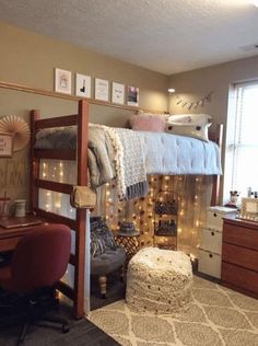 a bedroom with a loft bed, desk and chair next to a window covered in fairy lights