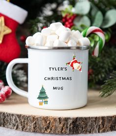 a white christmas mug filled with marshmallows on top of a wooden table