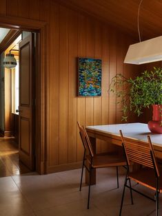 a dining room table with chairs and a vase filled with plants on top of it