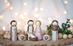 a nativity scene with figurines on a table next to balls and greenery