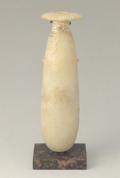 a white vase sitting on top of a wooden base