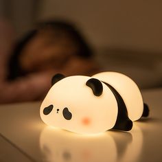 a panda bear night light sitting on top of a table next to a sleeping person