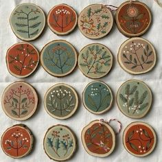 twelve embroidered ornaments are arranged in rows on a table