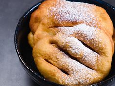 powdered sugar covered pastry in a black bowl