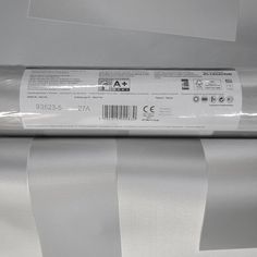 a roll of white paper sitting on top of a metal object with a barcode printed on it