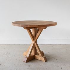 a wooden table sitting on top of a cement floor next to a white wall in an empty room