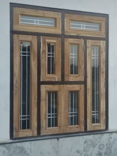 a wooden window on the side of a building with glass panes and wood trim