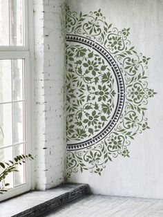 the wall is decorated with green and black designs on it, along with a window sill