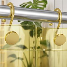 two clear boxes are hanging from a metal bar with gold circles on the top and bottom