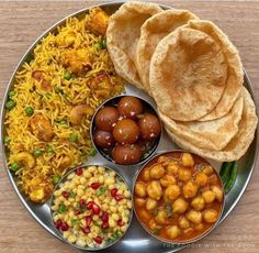 a metal plate topped with lots of different types of food next to rice and pita bread