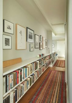 a long bookshelf filled with lots of books on top of a wooden floor