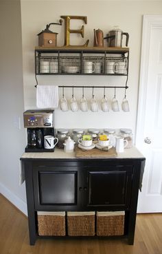 the coffee bar has many cups on it and is next to a wall mounted shelf