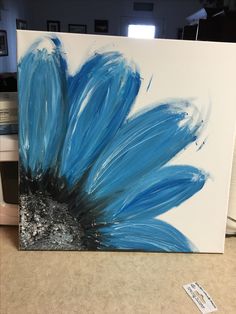 a blue flower painted on a white canvas