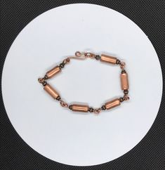 a white plate topped with a bracelet and a small metal bead on top of it