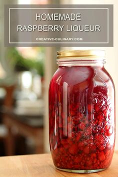 a jar filled with raspberry liquid sitting on top of a wooden table