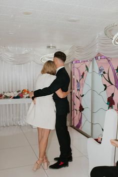 a man and woman are hugging in the middle of a dance floor with white drapes