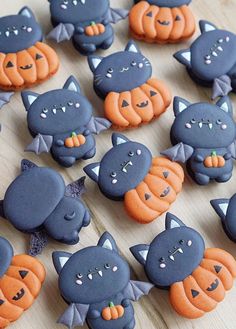 there are many decorated cookies that look like cats and pumpkins on the wooden table