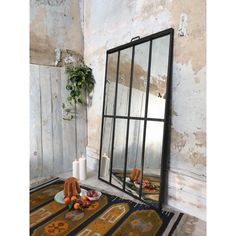 a large mirror sitting on top of a rug next to a candle and potted plant