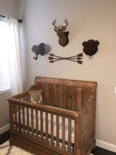 a wooden crib in the corner of a room with deer heads on the wall