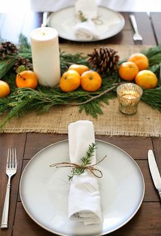 a place setting with oranges and pine cones