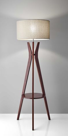 a wooden table lamp with a white shade on the top and bottom shelf in front of it